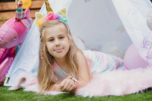 A child in a teepee for her Unicorn-themed party