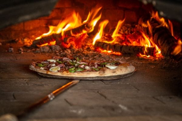 A pizza in a wood-fire oven