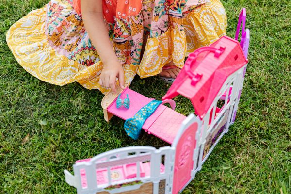 A girl playing with Barbie's dream house on the lawn