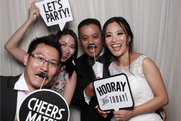 A group of wedding guests photo bombing a photo booth