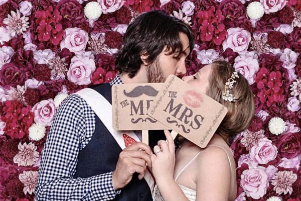 A newly married couple kissing in a photo booth