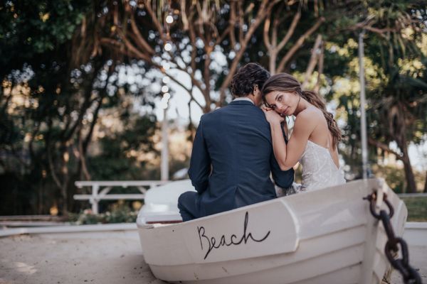A wedding couple sitting in a boat after their beach wedding