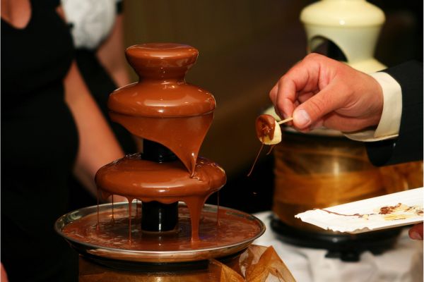 A couple dipping treats into a chocolate fountain