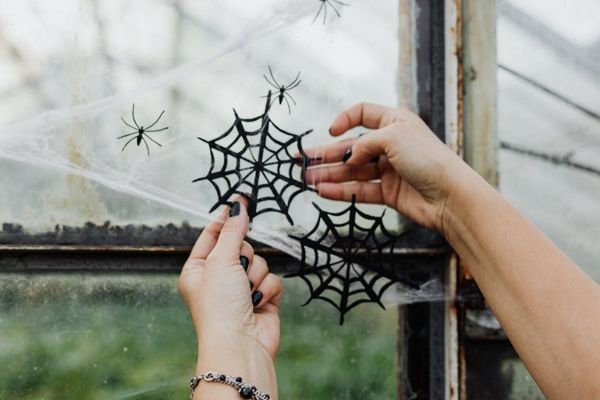 A person handing cobweb decorations for Halloween