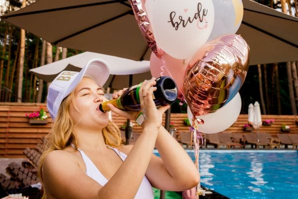 A bride-to-be drinking out of a champagne bottle